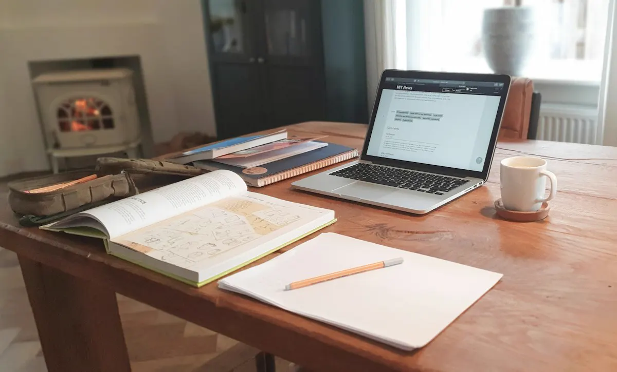 Mesa de estudio con libros abiertos y un portátil