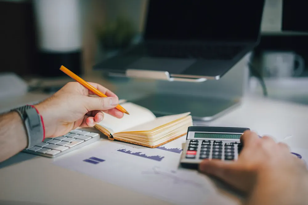 Persona revisando cuentas con calculadora y libreta