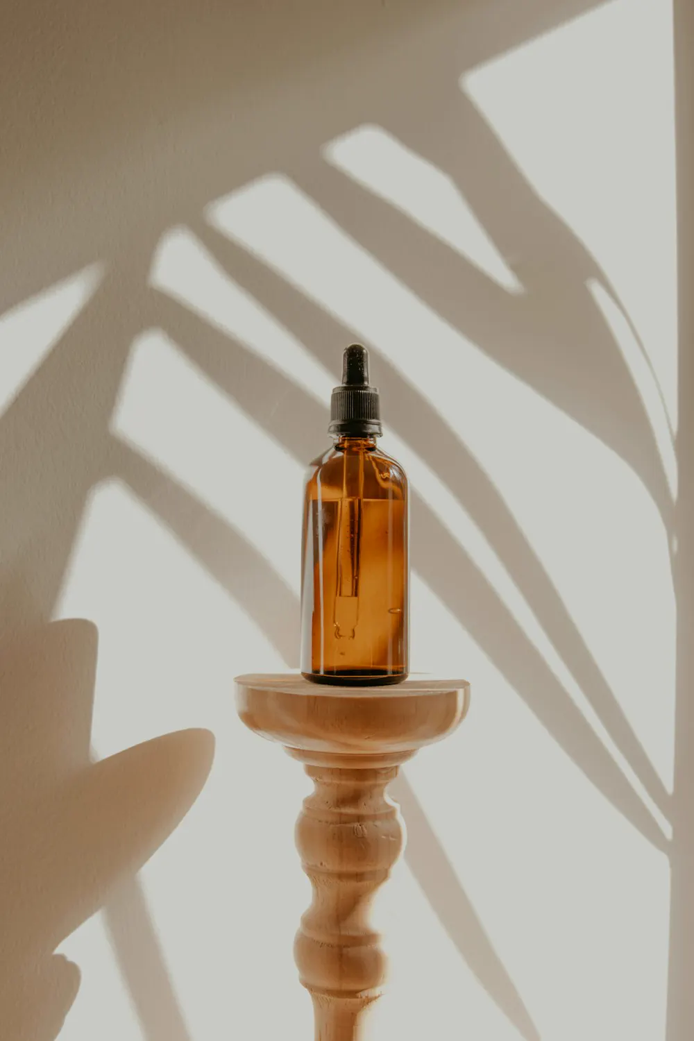 Frasco de sérum ámbar sobre un pedestal de madera