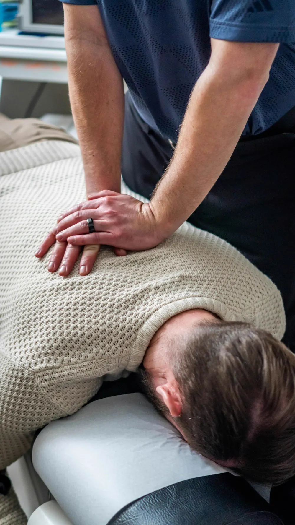 Manos del fisioterapeuta sobre la espalda alta de un paciente tumbado