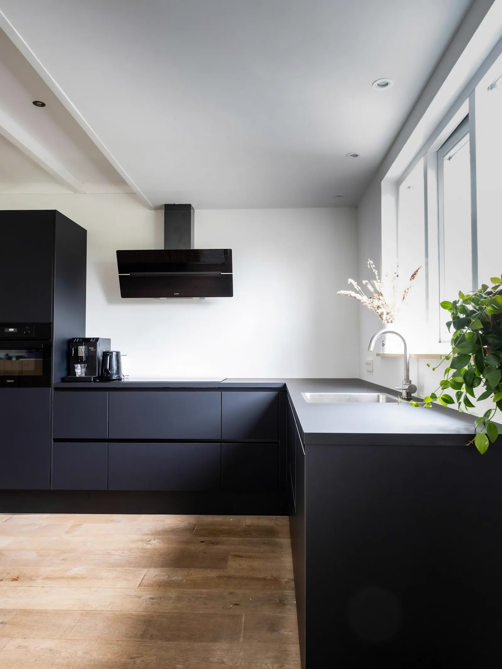 Cocina reformada con muebles negros y encimera de piedra