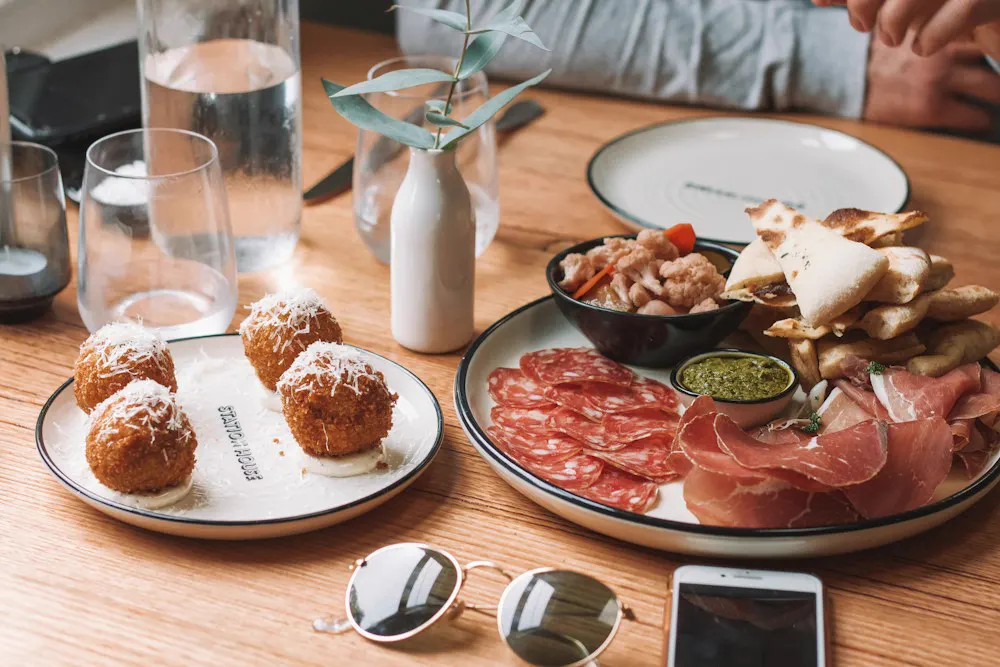 Croquetas y embutido en platos sobre mesa de madera