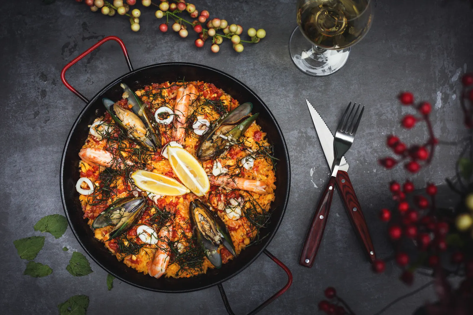Paella de marisco sobre una mesa oscura con cubiertos